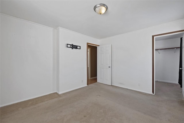 unfurnished bedroom featuring light colored carpet, ornamental molding, a closet, and a walk in closet