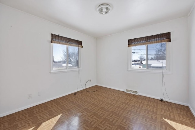 unfurnished room featuring parquet flooring and plenty of natural light