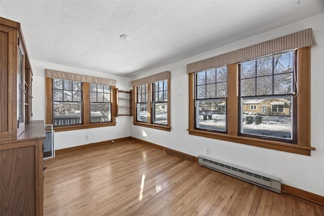 unfurnished room with a baseboard radiator, a textured ceiling, and light hardwood / wood-style floors