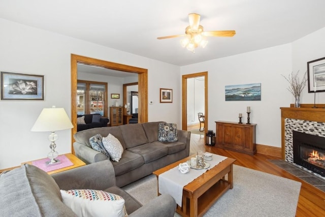 living room featuring hardwood / wood-style flooring, a tile fireplace, and ceiling fan