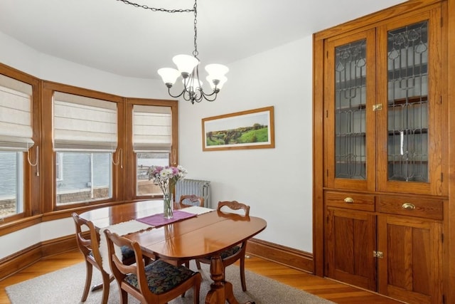 dining area with hardwood / wood-style flooring, radiator heating unit, and a chandelier