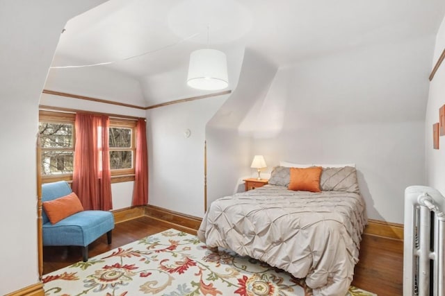 bedroom featuring lofted ceiling, radiator heating unit, and hardwood / wood-style floors