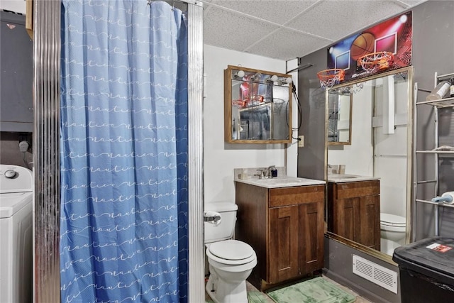 bathroom with curtained shower, vanity, a drop ceiling, washer / dryer, and toilet