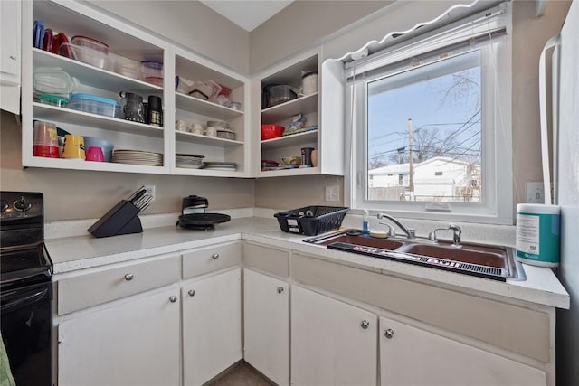 kitchen with black range with electric cooktop, sink, and white cabinets