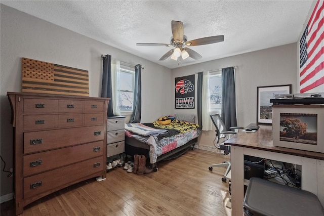 bedroom with ceiling fan, a textured ceiling, and light wood-type flooring