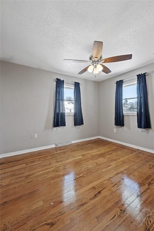 unfurnished room with ceiling fan, a healthy amount of sunlight, and hardwood / wood-style floors