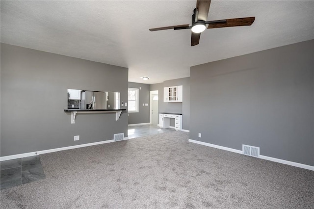 unfurnished living room with ceiling fan, a textured ceiling, and carpet flooring