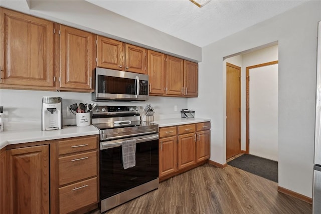 kitchen featuring stainless steel appliances, a textured ceiling, and dark hardwood / wood-style flooring