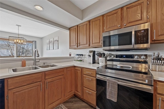 kitchen featuring pendant lighting, stainless steel appliances, a chandelier, and sink