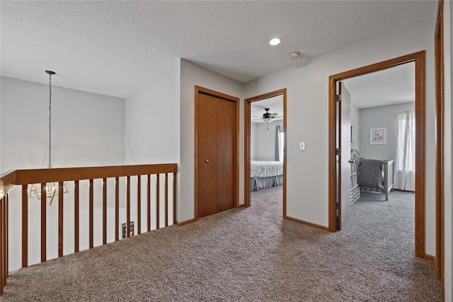 hall with carpet floors and a textured ceiling