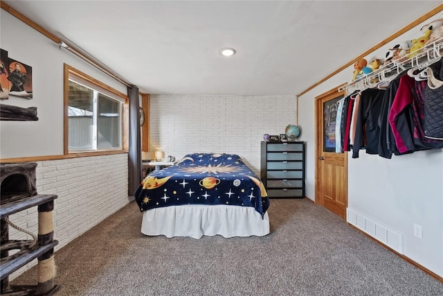 bedroom with carpet floors and brick wall