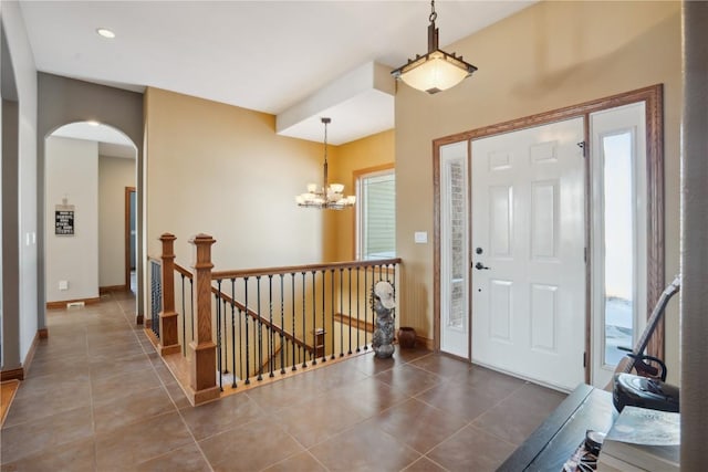 foyer featuring dark tile patterned floors and a notable chandelier