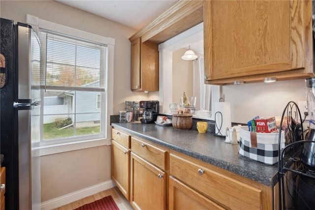 kitchen with hardwood / wood-style floors, decorative light fixtures, and stainless steel refrigerator