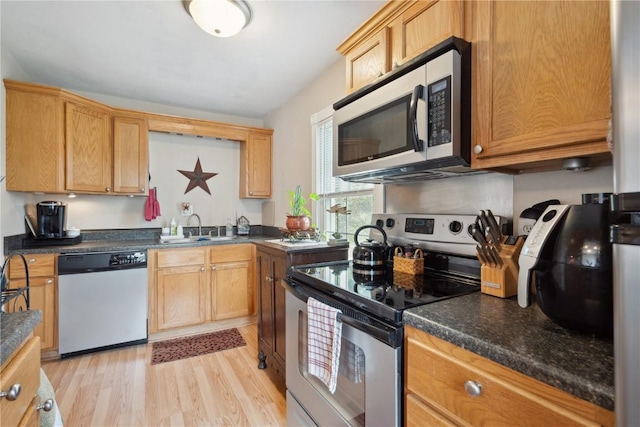 kitchen with stainless steel appliances, sink, and light hardwood / wood-style floors