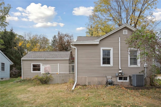 rear view of house with central AC and a lawn