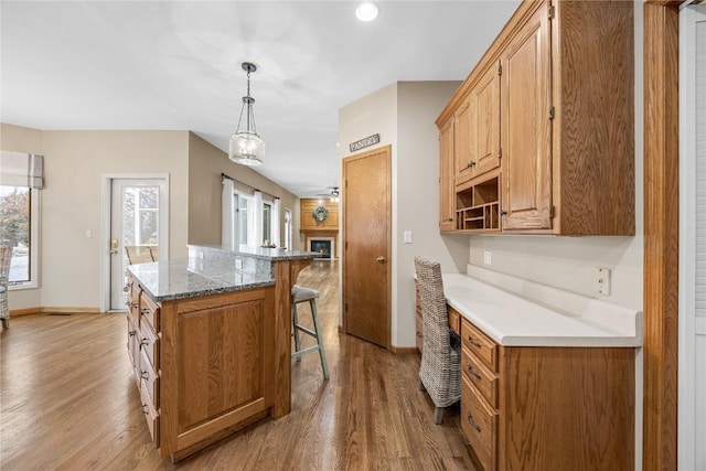 kitchen with a center island, light hardwood / wood-style flooring, decorative light fixtures, light stone countertops, and a breakfast bar area