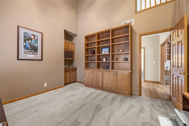 carpeted empty room featuring built in desk and a towering ceiling