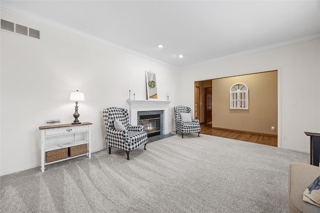 sitting room with a tile fireplace, carpet, and ornamental molding