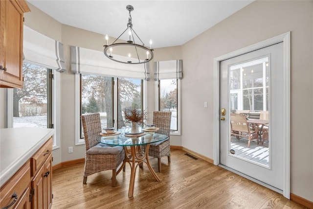 dining area with light wood-type flooring and an inviting chandelier