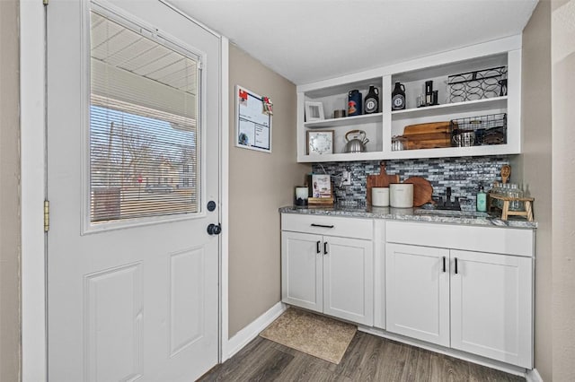 bar featuring tasteful backsplash, dark stone countertops, dark hardwood / wood-style floors, and white cabinets