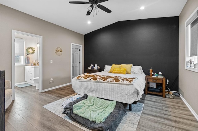 bedroom with hardwood / wood-style floors, vaulted ceiling, ceiling fan, and ensuite bathroom