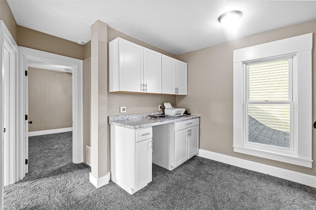 kitchen with white cabinetry, dark carpet, and a textured ceiling