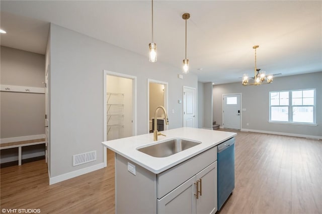 kitchen with a center island with sink, sink, light wood-type flooring, decorative light fixtures, and stainless steel dishwasher