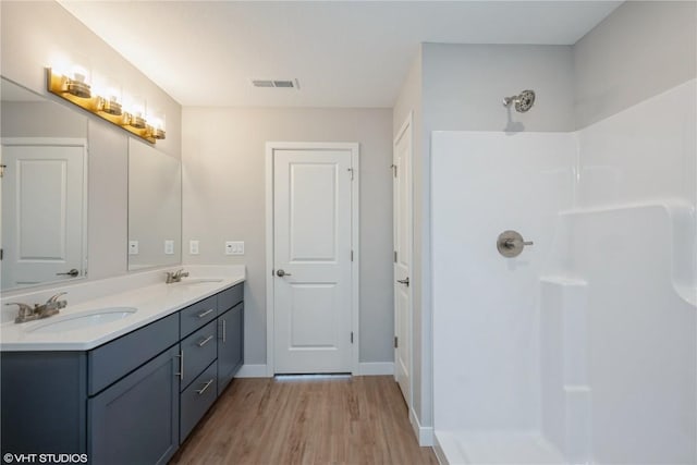 bathroom with hardwood / wood-style flooring, a shower, and vanity