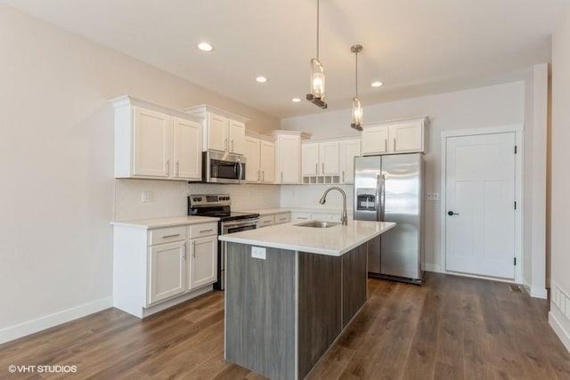 kitchen featuring appliances with stainless steel finishes, sink, backsplash, white cabinetry, and hanging light fixtures