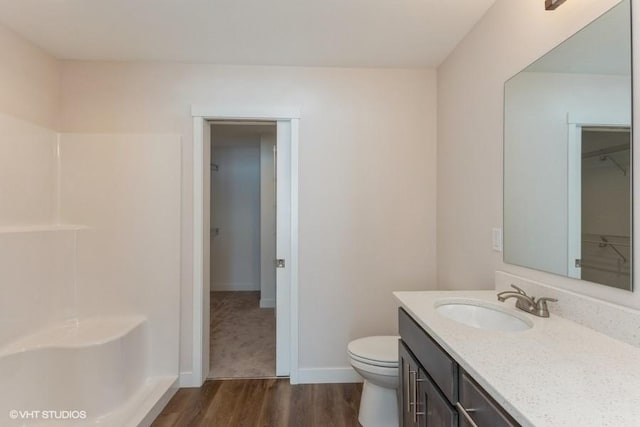 bathroom featuring toilet, hardwood / wood-style flooring, vanity, and walk in shower