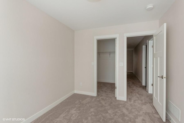 unfurnished bedroom with a closet, a spacious closet, and light colored carpet