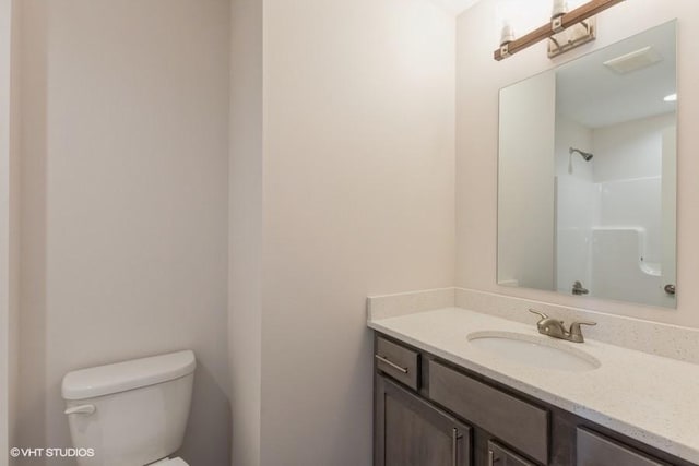 bathroom with toilet, vanity, and a shower