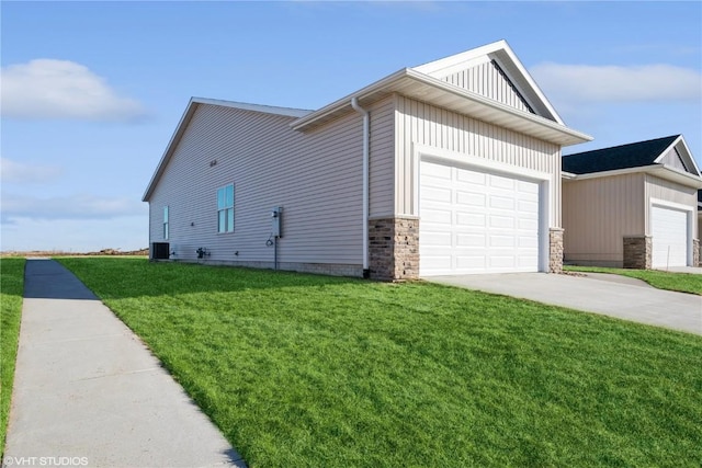 view of side of property with a lawn, a garage, and central AC unit