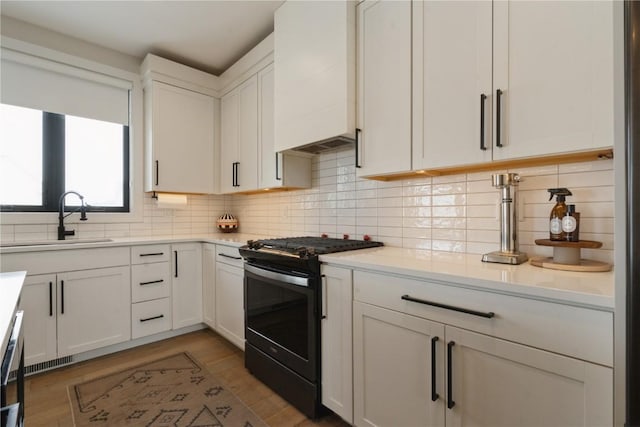 kitchen with white cabinetry, sink, range with gas cooktop, and decorative backsplash