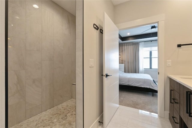 bathroom with tiled shower, tile patterned flooring, and vanity