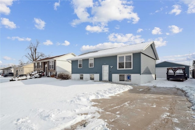 snow covered rear of property featuring a garage