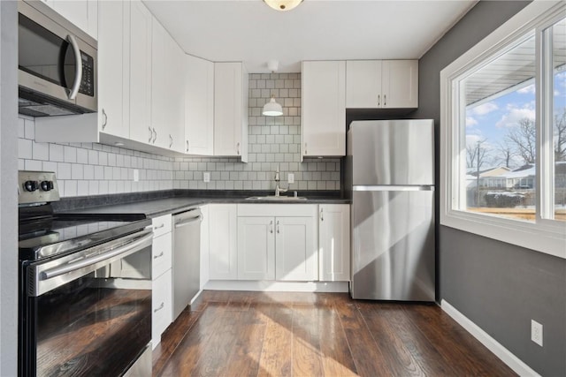 kitchen with dark hardwood / wood-style flooring, sink, backsplash, appliances with stainless steel finishes, and white cabinets