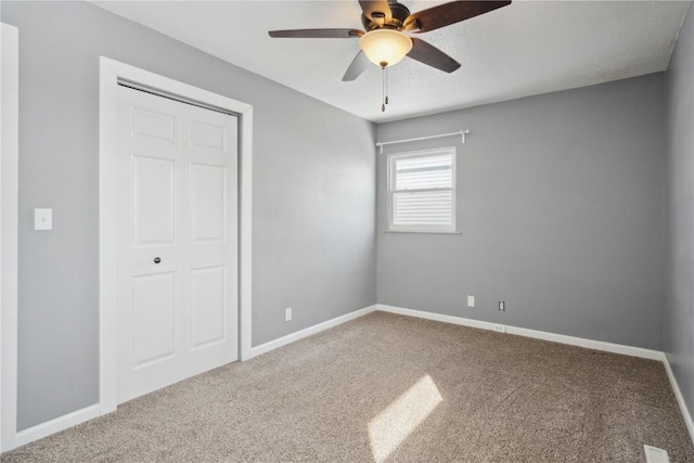 unfurnished bedroom featuring carpet, a closet, and ceiling fan