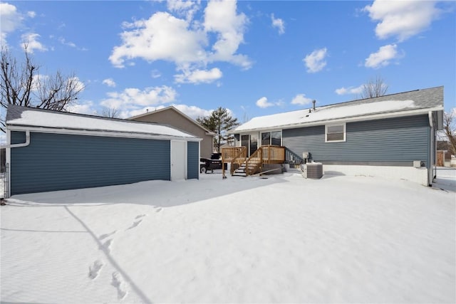 snow covered back of property featuring a garage and an outbuilding