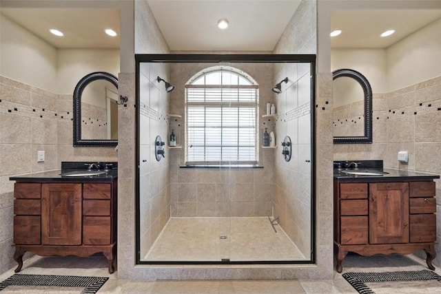 bathroom with tile walls, vanity, and walk in shower