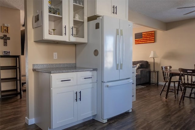 kitchen featuring dark hardwood / wood-style floors, white cabinetry, a textured ceiling, and white refrigerator