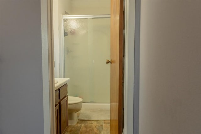 bathroom with toilet, vanity, and a shower with shower door