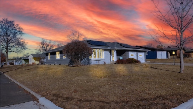 ranch-style home with a lawn and solar panels