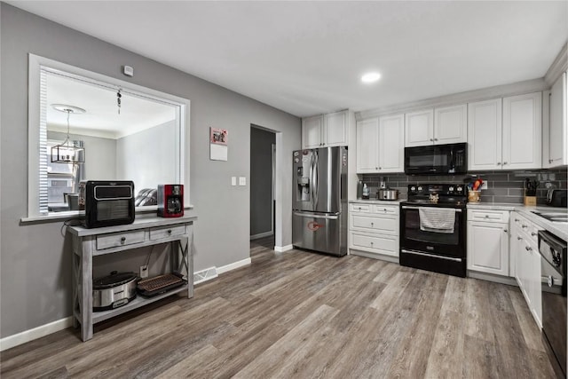 kitchen featuring white cabinetry, black appliances, and decorative backsplash