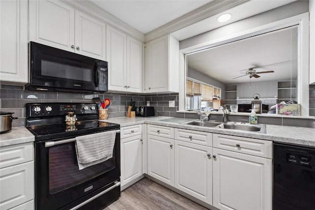 kitchen with sink, light hardwood / wood-style floors, black appliances, white cabinets, and decorative backsplash