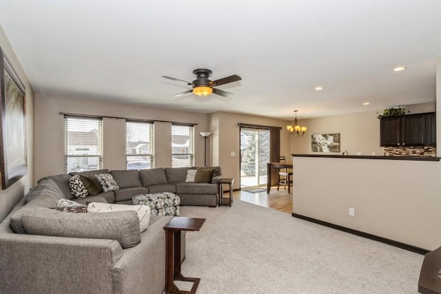 living room featuring ceiling fan with notable chandelier and light carpet