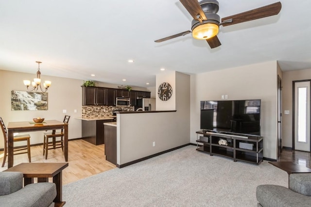 carpeted living room with ceiling fan with notable chandelier