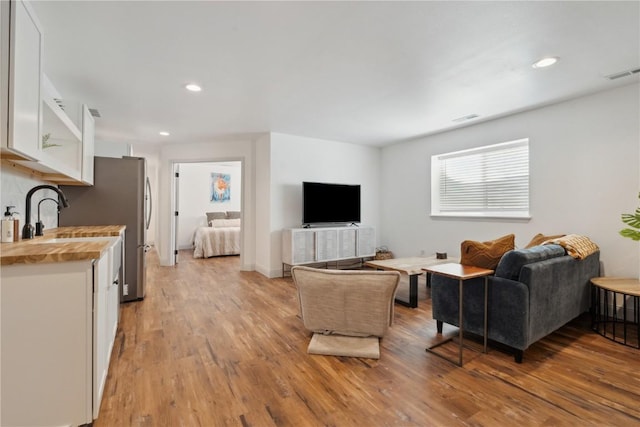 living room featuring light wood-style floors, recessed lighting, and visible vents