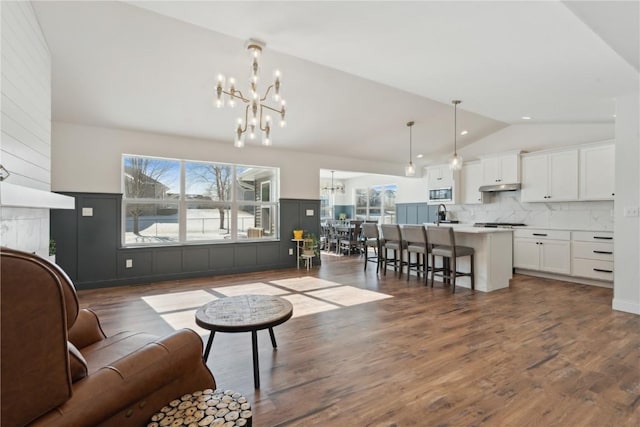 living room with dark wood-style floors, high vaulted ceiling, and a notable chandelier