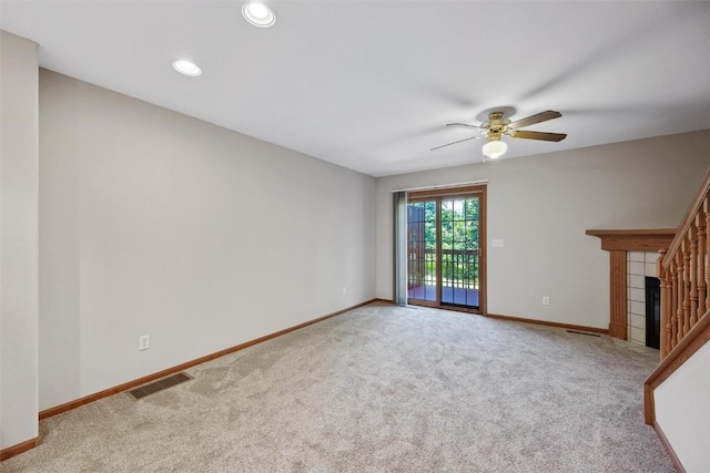 unfurnished living room with ceiling fan, light colored carpet, and a fireplace